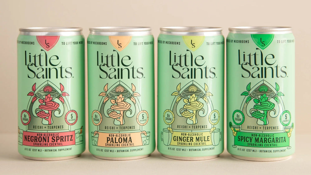 Four cans of 'Little Saints' drinks on a beige background